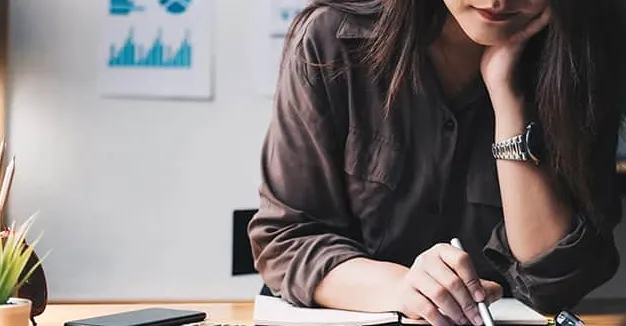 Mujer sentada en un escritorio con una calculadora después de aprender a contar celdas que contienen texto específico en Excel