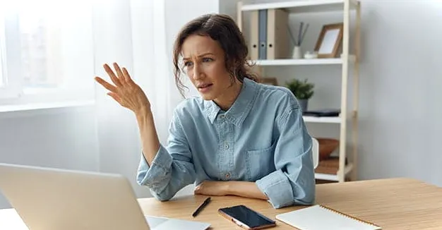 Mujer frustrada mirando la pantalla de una computadora mientras aprende a arreglar #REF en Excel