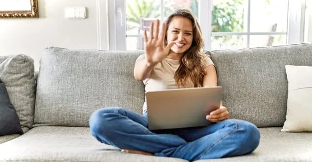 Mujer sentada en un sofá con una computadora portátil dando la señal de chocar los cinco después de aprender a redondear al 5 más cercano en Excel