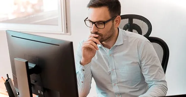 Hombre pensando en funciones avanzadas de Excel mientras mira la pantalla de una computadora.